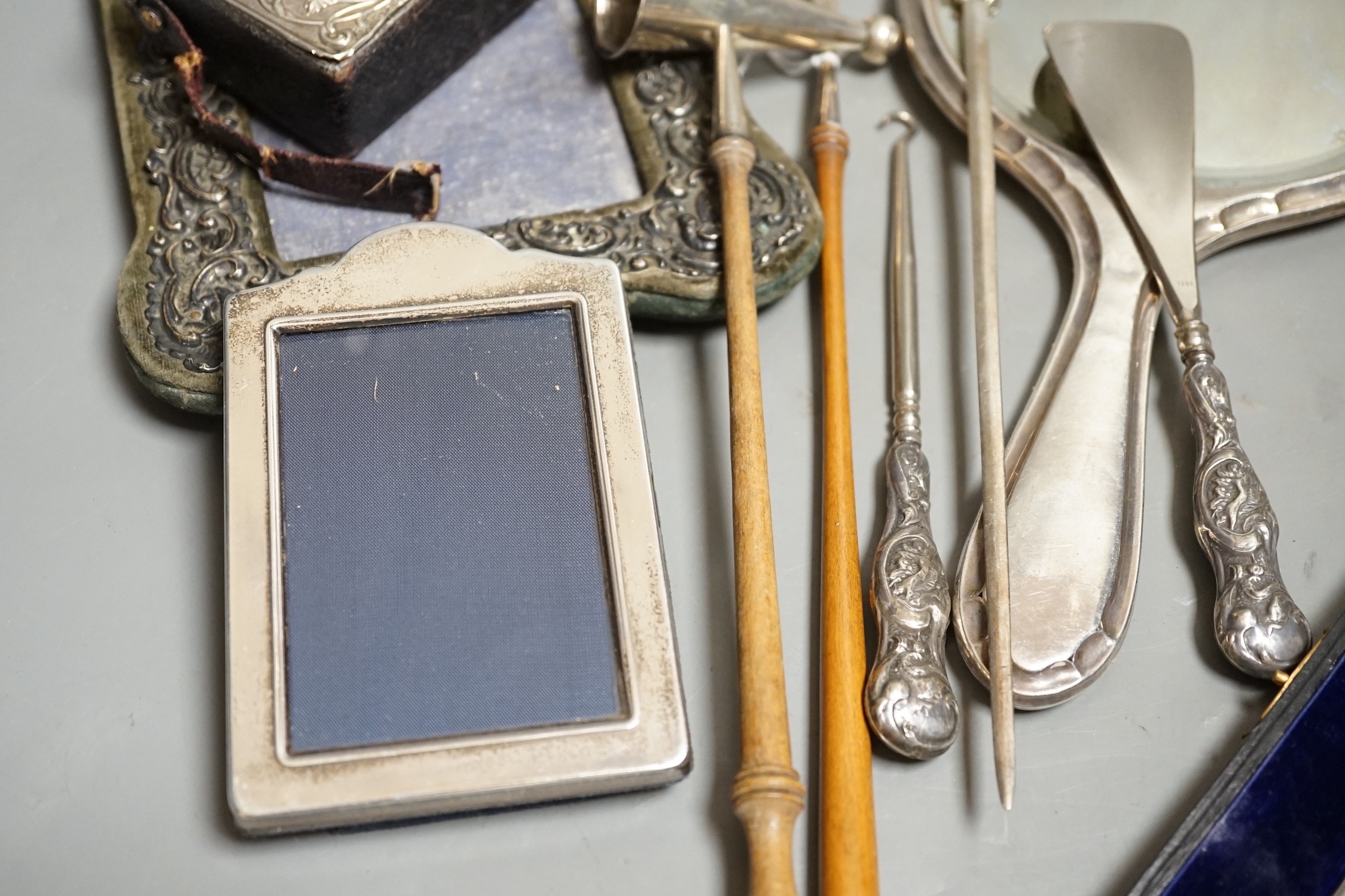 A group of small silver including two mounted photograph frames, one Birmingham, 1901, a mounted bible case, candlestick snuffer, coaster, etc.